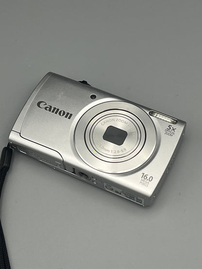 Angled front and underside view of a silver Canon PowerShot A2500 with its lens closed