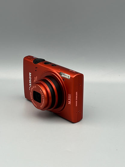 Red Canon PowerShot ELPH 110 HS viewed from the opposite front corner with its lens extended