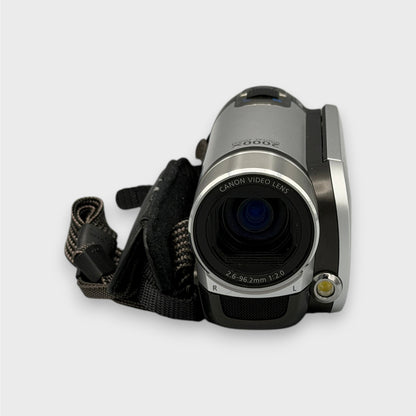 Close-up of the Canon FS200 camcorder lens and front light beside the black hand strap