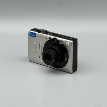Silver Canon PowerShot SD770 IS viewed from the opposite front corner with its lens extended