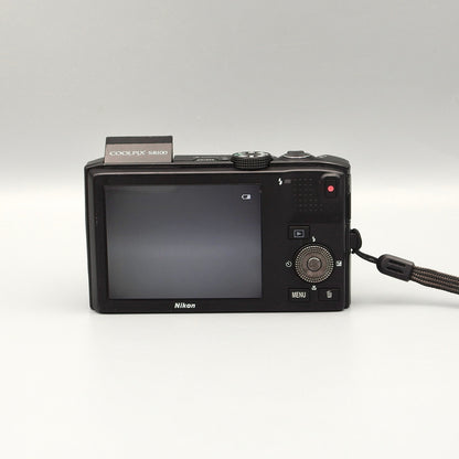 Nikon Coolpix S8100 rear view showing the LCD screen, control dial and raised flash.