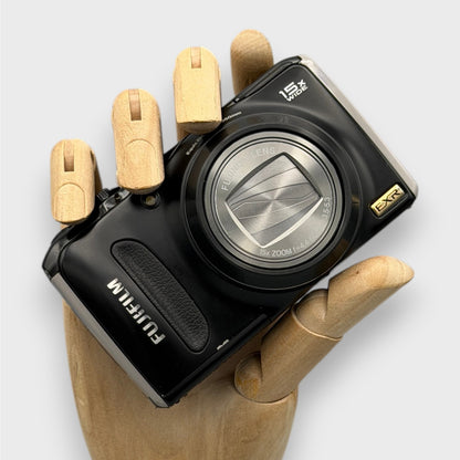 Black Fujifilm FinePix F300EXR held in a wooden display hand with its lens closed.