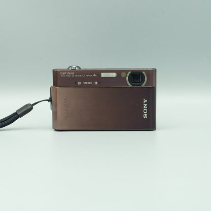 Front view of a brown Sony Cyber-shot DSC-T900 with its sliding lens cover open