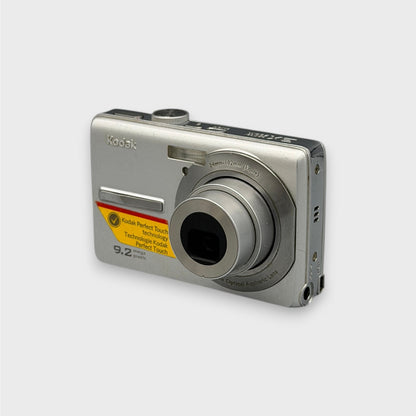 Silver Kodak EasyShare M320 viewed from the opposite front corner with its lens extended