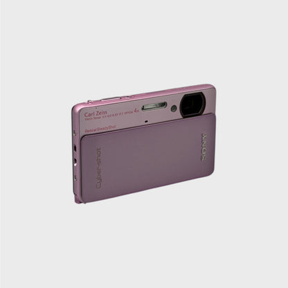 Angled front view of a pink Sony Cyber-shot DSC-TX5 showing the exposed lens and top controls