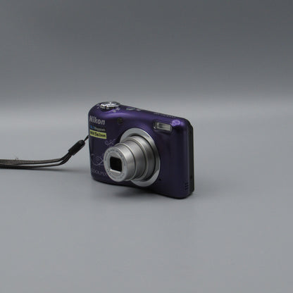 Purple Nikon Coolpix A10 viewed from a front angle showing its extended silver lens and patterned body.