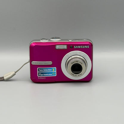 Front view of a pink Samsung S860 digital camera with its lens extended