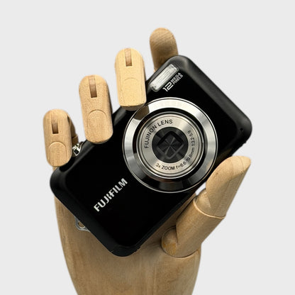 Black Fujifilm FinePix JV100 with its lens closed, held in a wooden display hand