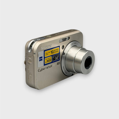 Angled front view of a gold Sony Cyber-shot DSC-N2 showing its extended silver lens and rounded side panel