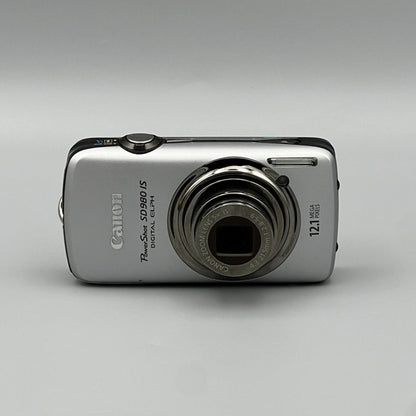 Front view of a silver Canon PowerShot SD980 IS with its lens extended