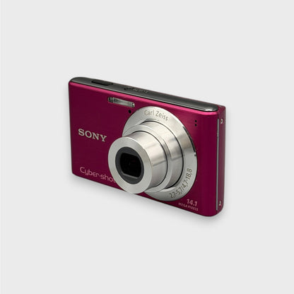 Pink Sony Cyber-shot DSC-W530 viewed from a front angle showing the extended lens and side panel.