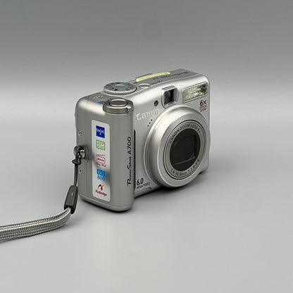 Angled front view of a silver Canon PowerShot A700 showing the grip, top controls and closed lens