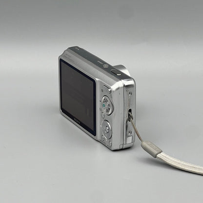 Rear corner view of a silver Sony Cyber-shot DSC-W220 showing its screen, controls and wrist strap attachment