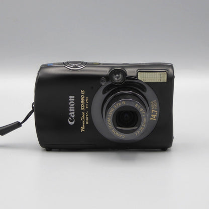Front view of a black Canon PowerShot SD990 IS digital camera with its lens extended
