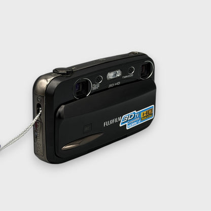 Fujifilm FinePix REAL 3D W3 viewed from the opposite front corner with its lens cover open and wrist strap visible