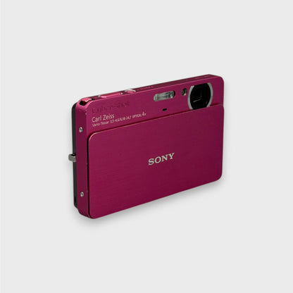 Angled front view of a pink Sony Cyber-shot DSC-T700 with its lens cover open and left edge visible