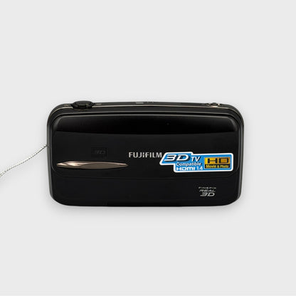 Front view of a black Fujifilm FinePix REAL 3D W3 with its sliding lens cover closed