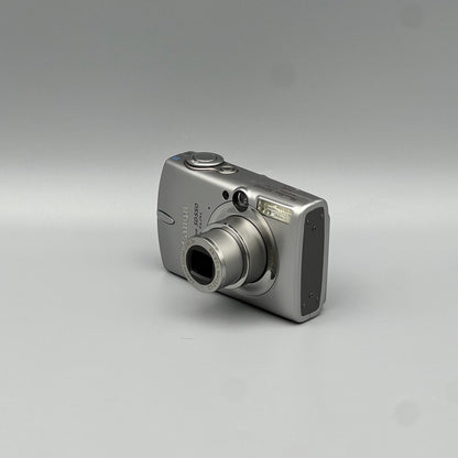 Silver Canon PowerShot SD550 viewed from a front angle showing the extended lens and side panel.