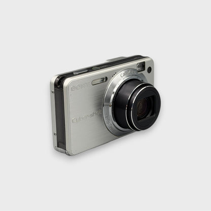 Silver Sony Cyber-shot DSC-W150 viewed from a front angle with its lens extended.