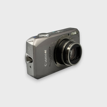 Angled front view of a silver Canon PowerShot SD4500 IS showing the extended lens and top controls