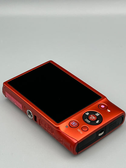 Red Canon PowerShot ELPH 110 HS lying face down with its LCD screen, control pad and underside visible