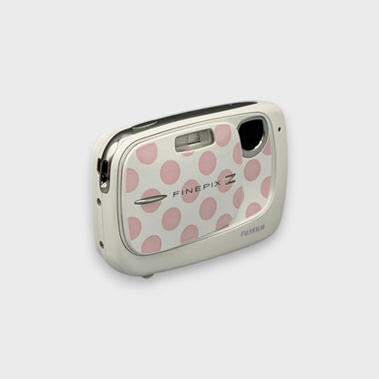 White Fujifilm FinePix Z37 with pink polka dots, viewed from a front angle with its lens exposed.