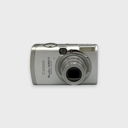 Front view of a silver Canon PowerShot SD850 IS digital camera with its lens extended