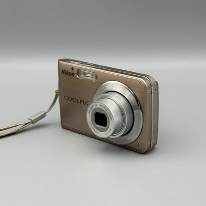 Bronze Nikon Coolpix S210 viewed from a front angle with its lens extended and top controls visible.