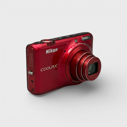 Red Nikon Coolpix S6500 viewed from a front angle with its lens extended.