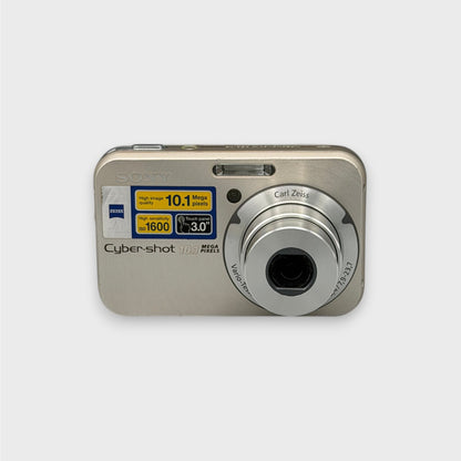 Front view of a gold Sony Cyber-shot DSC-N2 with its silver lens extended and feature stickers visible