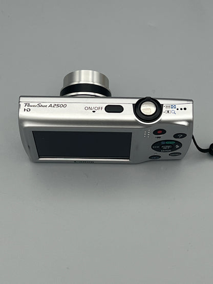 Top and rear view of a silver Canon PowerShot A2500 showing the shutter button, power button and extended lens