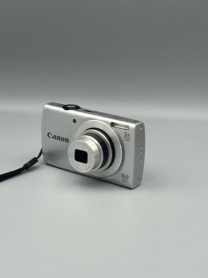 Silver Canon PowerShot A2500 viewed from the opposite front corner with its lens extended