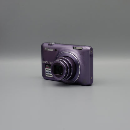 Purple Nikon Coolpix S6400 viewed from a front angle with its lens extended and top controls visible.