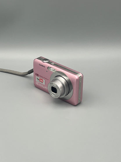 Pink Casio Exilim EX-Z85 viewed from a front angle with its lens extended and top controls visible.