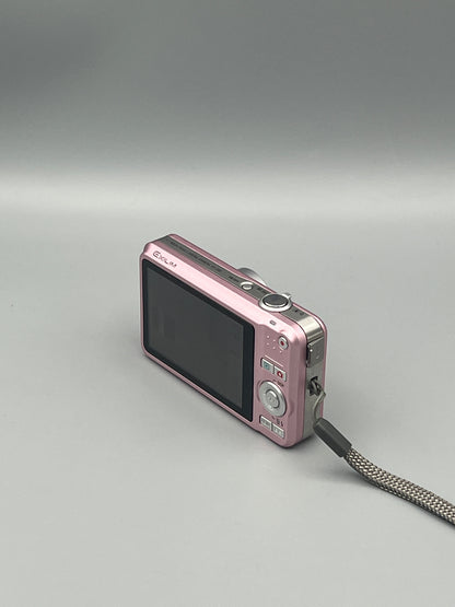 Pink Casio Exilim EX-Z85 viewed from a rear angle showing the LCD screen, controls and side panel.
