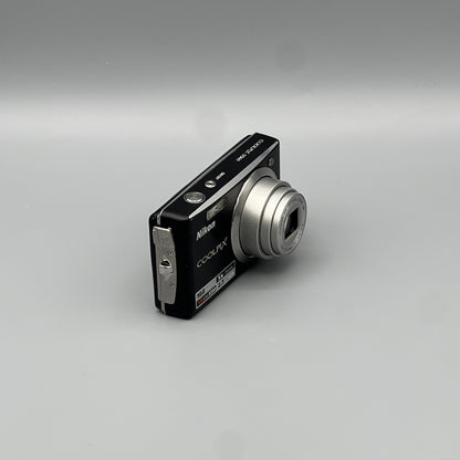 Angled front view of a black Nikon Coolpix S560 showing its extended lens, silver side panel and top buttons