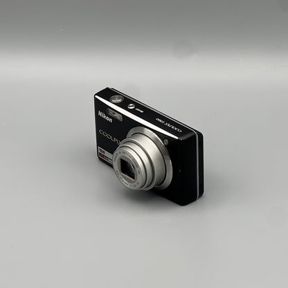 Black Nikon Coolpix S560 viewed from the opposite front corner with its silver lens extended