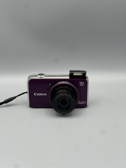Front view of a purple Canon PowerShot SX220 HS with the lens extended and flash raised