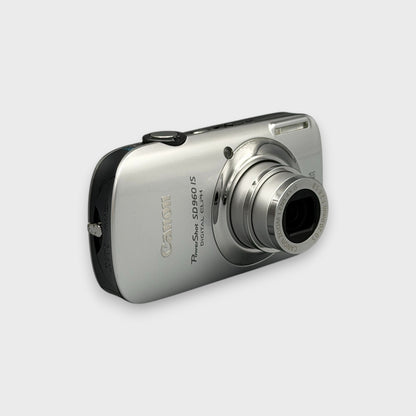 Silver Canon PowerShot SD960 IS viewed from a front angle with its lens extended.