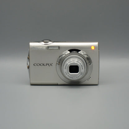 Front view of a silver Nikon Coolpix S4000 with its lens extended and an orange front indicator illuminated