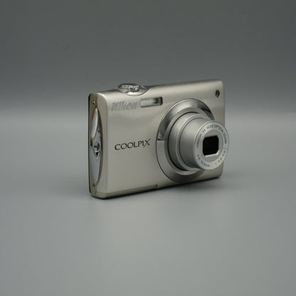 Angled front view of a silver Nikon Coolpix S4000 showing its extended lens and sculpted side panel