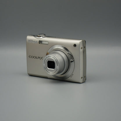 Silver Nikon Coolpix S4000 viewed from the opposite front corner with its lens extended