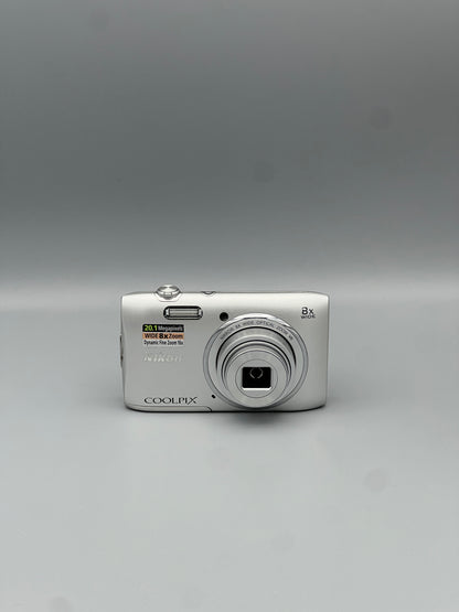 Front view of a silver Nikon Coolpix S3600 with its lens extended