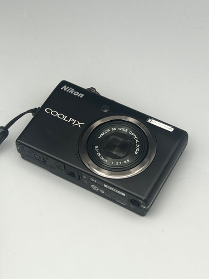 Black Nikon Coolpix S570 viewed from above at a front angle with its lens closed.