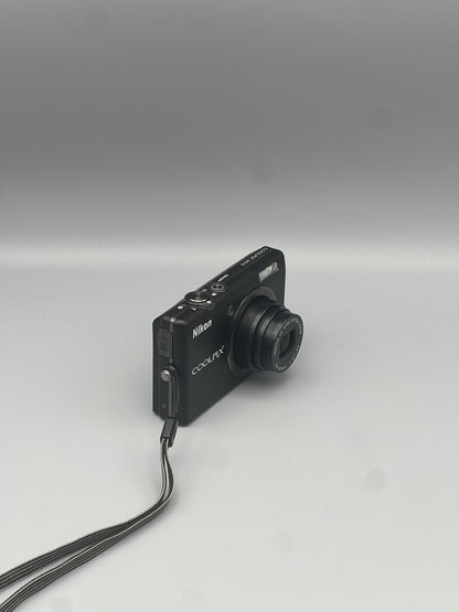 Black Nikon Coolpix S570 viewed from a front angle with its lens extended.
