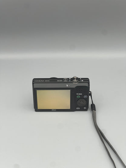 Nikon Coolpix S570 rear view showing the LCD screen and controls with the wrist strap beside it.