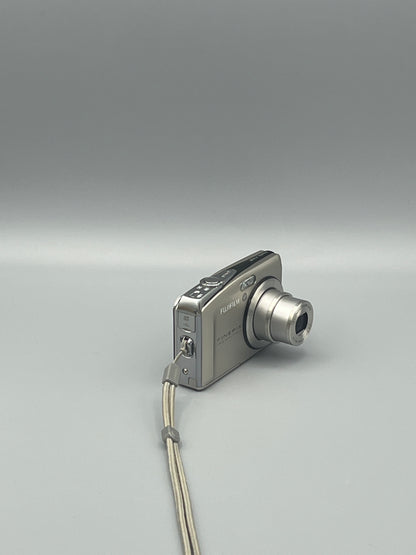 Silver Fujifilm FinePix F50FD viewed from a front angle showing the extended lens and side panel.