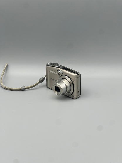Silver Fujifilm FinePix F50FD viewed from a front angle with its extended lens and top controls visible.