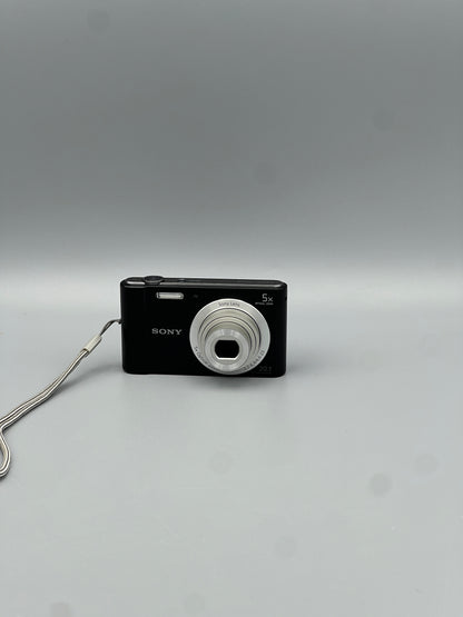 Black Sony Cyber-shot DSC-W800 front view with its silver lens extended and wrist strap attached.