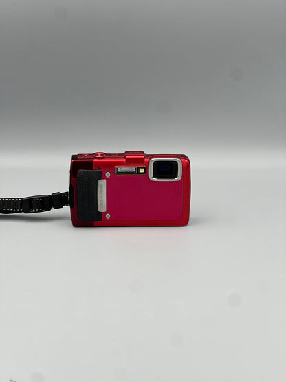 Front view of a red Olympus Stylus Tough TG-830 showing the corner lens, flash and black grip
